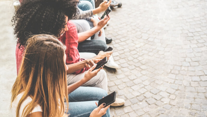 group of teens surfing on their mobile phone